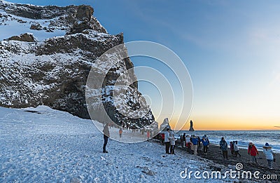 Reynisfjara beach completely covered in snow and the basalt formations illuminated by the last rays of the sun from the horizon Editorial Stock Photo