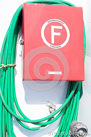 Rhodes, Greece, June 6, 2019: Red colored box and rolled green fire hose on white wall on the Dodekanisos express boat Editorial Stock Photo