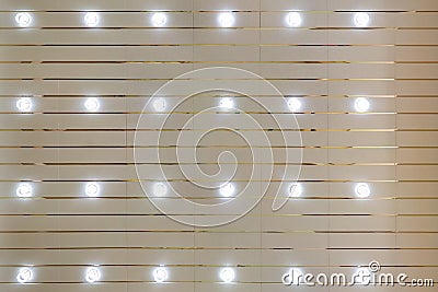 Rhythmic texture on suspended ceiling with rows of halogen spots lamps and drywall construction with chandelier. Stretch ceiling Stock Photo