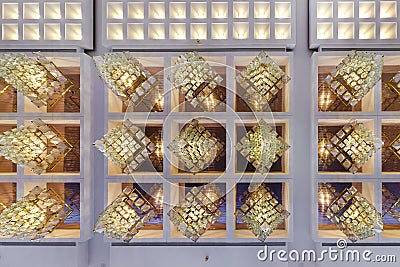 Rhythmic texture on suspended ceiling with rows of halogen spots lamps and drywall construction with chandelier. Stretch ceiling Stock Photo