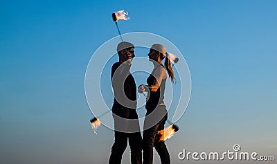 Rhythmical swinging. Couple of dancers swing burning poi blue sky. Fiery poi swinging. Fire performance. Fun and Stock Photo