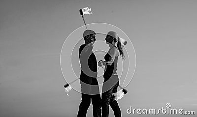 Rhythmical swinging. Couple of dancers swing burning poi blue sky. Fiery poi swinging. Fire performance. Fun and Stock Photo