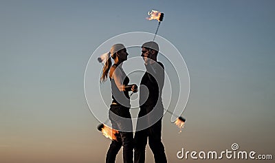 Rhythmical swinging. Couple of dancers swing burning poi blue sky. Fiery poi swinging. Fire performance. Fun and Stock Photo