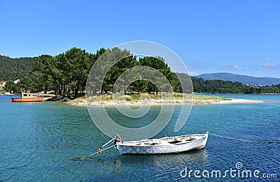 Beach with turquoise water, pine trees and fishing boats. Galicia, Spain. Stock Photo