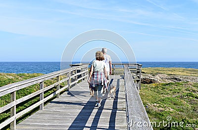 A couple is walking the dogs on a beach boardwalk close to As Catedrais beach. Ribadeo, Spain. Editorial Stock Photo