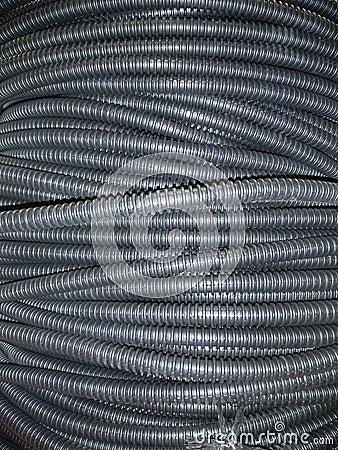 Ribbed black plastic pipes are twisted in concentric circles. Stock Photo