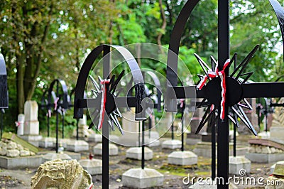 Ribbon with national colours of Poland tied up to the old cross on the cemetery. Rebelion uprising concept. Stock Photo