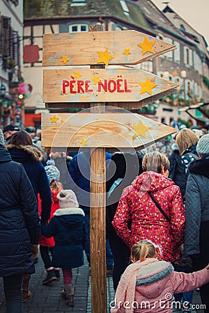 RibeauvillÃ©, Alsace, France - December 8, 2019: wooden signpost showing dirrection to Santa Claus PÃ¨re NoÃ«l. Big crowd on the Editorial Stock Photo