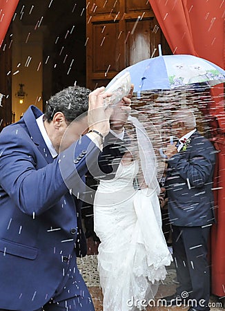 Rice being thrown at bride and groom as they exit by the church Stock Photo