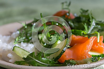 Rice with fresh salade and raw salmon close up. Rucola with cucamber and fish with rice. Healthy tasty food. Rice with vegetables. Stock Photo