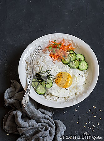 Rice with fried egg, pickled carrots, cucumber and seaweed. Healthy diet food concept. Top view Stock Photo