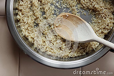 Rice frying and oiling in ghee on steel pan closeup, process of cooking asian indian basmati ghee rice Stock Photo