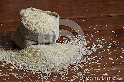 Rice grains are poured into a linen bag. Stock Photo