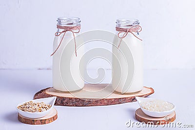 Rice and oat vegan milk in glass bottles on a wooden stand Stock Photo