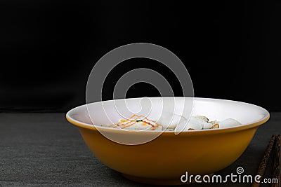 Rice stick noodles in broth with pork and meatballs in bowl on tile table Stock Photo