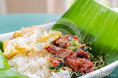 Rice topped with stir-fried pork, basil leaves and chili served Stock Photo