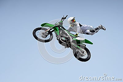 Ricer in a white protective uniform and helmet shares a stunt in the air on a motorcycle. Stock Photo