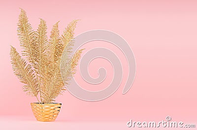 Rich bright interior with gold decorative fern branch in glossy pot on soft light pink background, copy space. Stock Photo