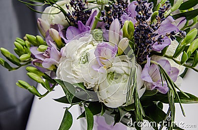 Rich bunch of violet fresia, white buttercup ranunculus peonies, green leaf, lilac lavender, roses, rosemary in bouquet Stock Photo