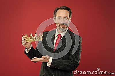 Rich reward. Mature businessman showing crown reward on red background. Successfil big boss awarding winner with Stock Photo