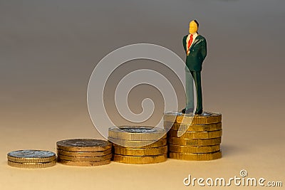 Rich successful business man standing on top of increasing piles of gold coins. Business career concept Stock Photo