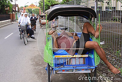 Rickshaw driver asleep in becak in Yogyakarta, Java, Indonesia Editorial Stock Photo