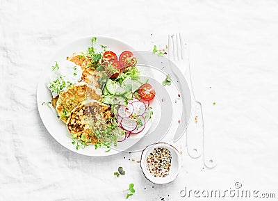 Ricotta zucchini fritters and fresh vegetables salad. Cucumbers, cherry tomatoes, radishes, micro greens and zucchini pancakes on Stock Photo