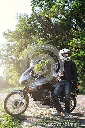 rider guy use smart phone in jeans biker jacket and helmet sit on tourist touring motorcycle. outdoors, dual sport adventure Stock Photo