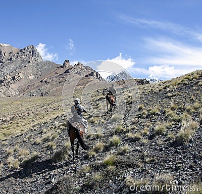 Riders on horses with weapons climb the mountain slope Editorial Stock Photo
