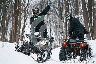 Riding the opposite ways. Two people are on the ATV in the winter forest Stock Photo