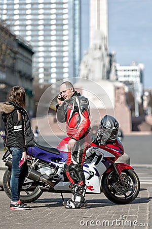 RIGA, LATVIA - APRIL 22, 2015: Unknown man on the street to bike talking on the phone Editorial Stock Photo