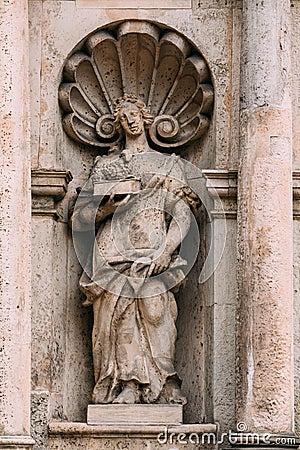 Riga Latvia. Close Ancient Statue Of Man With Lamb Lying On Book On The Facade Of St. Peter Church Stock Photo