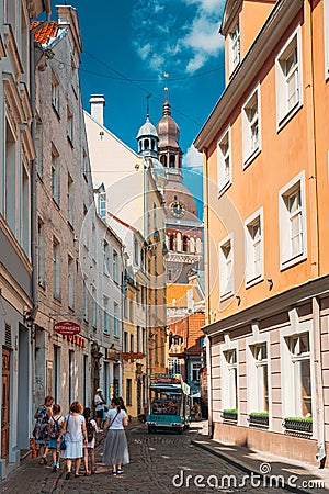 Riga, Latvia. People Walking On Narrow Cobbled Kramu Street Of Old Town With View Of Ancient Architectural Landmark Riga Editorial Stock Photo