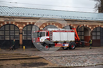 RIGA, LATVIA - MARCH 16, 2019: Fire truck is being cleaned - Driver washes firefighter truck at a depo - Old man passing Editorial Stock Photo