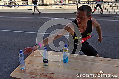 Riga, Latvia - May 19 2019: Caucasian Elite runner Tommy searching for sports drink Editorial Stock Photo