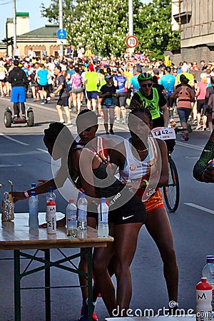 Riga, Latvia - May 19 2019: Three female Elite runners finding their sports drink from table during marathon Editorial Stock Photo