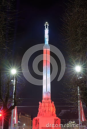 RIGA, LATVIA, NOVEMBER 17, 2017: Night view of the Freedom monument Brivibas piemineklis , decorated with fresh flowers Editorial Stock Photo