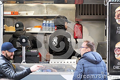06-03-2020 Riga, Latvia street sale and people concept - happy young saleswoman at food truck serving male customer Editorial Stock Photo
