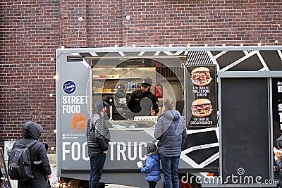 06-03-2020 Riga, Latvia street sale and people concept - happy young saleswoman at food truck serving male customer Editorial Stock Photo