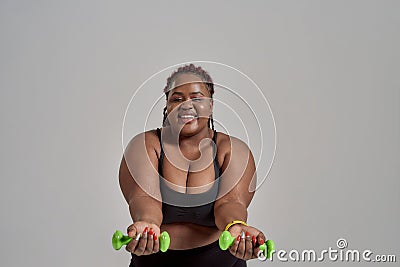 The right direction. Plump, plus size african american woman in sportswear reaching arms forward, holding green Stock Photo