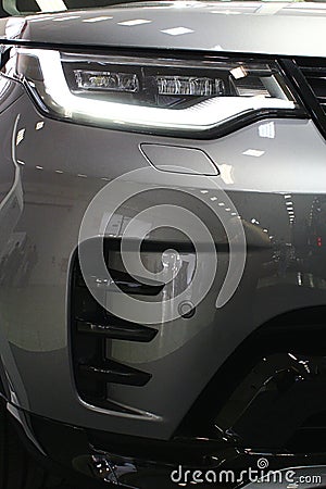 Right elegant headlight and part of massive front mask of premium english large SUV car Land Rover Discovery Editorial Stock Photo