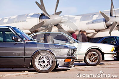 Right front side of two old european sport cars with plane on background Stock Photo