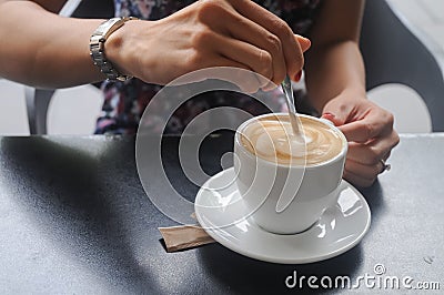 Right hand stir white freshly brewed Cappuccino coffee Stock Photo