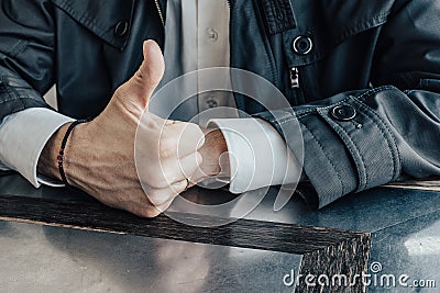 Right male hand with a rosary on the wrist and a thumb raised up. Close-up Stock Photo