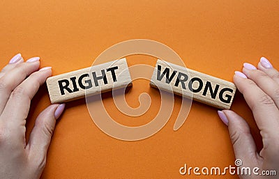 Right or Wrong symbol. Concept word Right or Wrong on wooden blocks. Businessman hand. Beautiful orange background. Business and Stock Photo