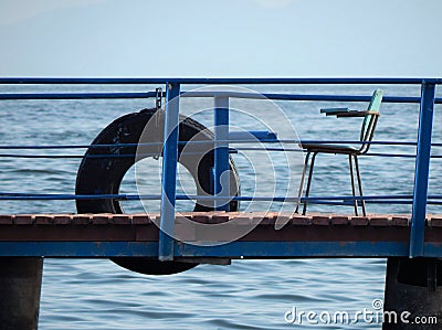 Ring-buoy and chair on the river pier. It`s all we need, I think Stock Photo