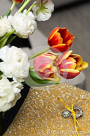 a ring is displayed on a small cushion beside flowers and tulips Stock Photo