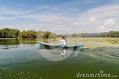 RIO DULCE, GUATEMALA - MARCH 10, 2016: Local indigenous woman paddling across Rio Dulce river, Guatema Editorial Stock Photo