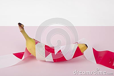 a ripe banana, wrapped in a red and white plastic ribbon Stock Photo