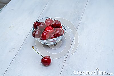 Ripe cherries in a glass bowl on a white wooden background Stock Photo